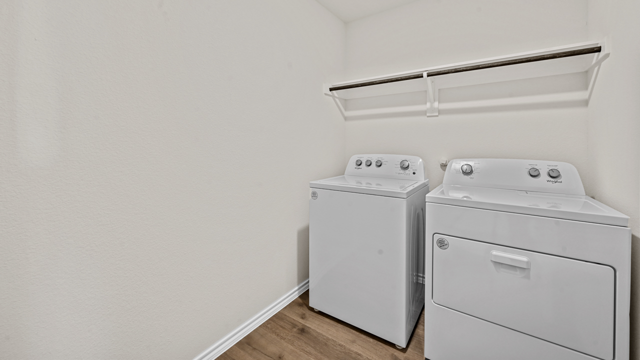 a laundry room with a washer and dryer and a shelf and rack for hanging clothing