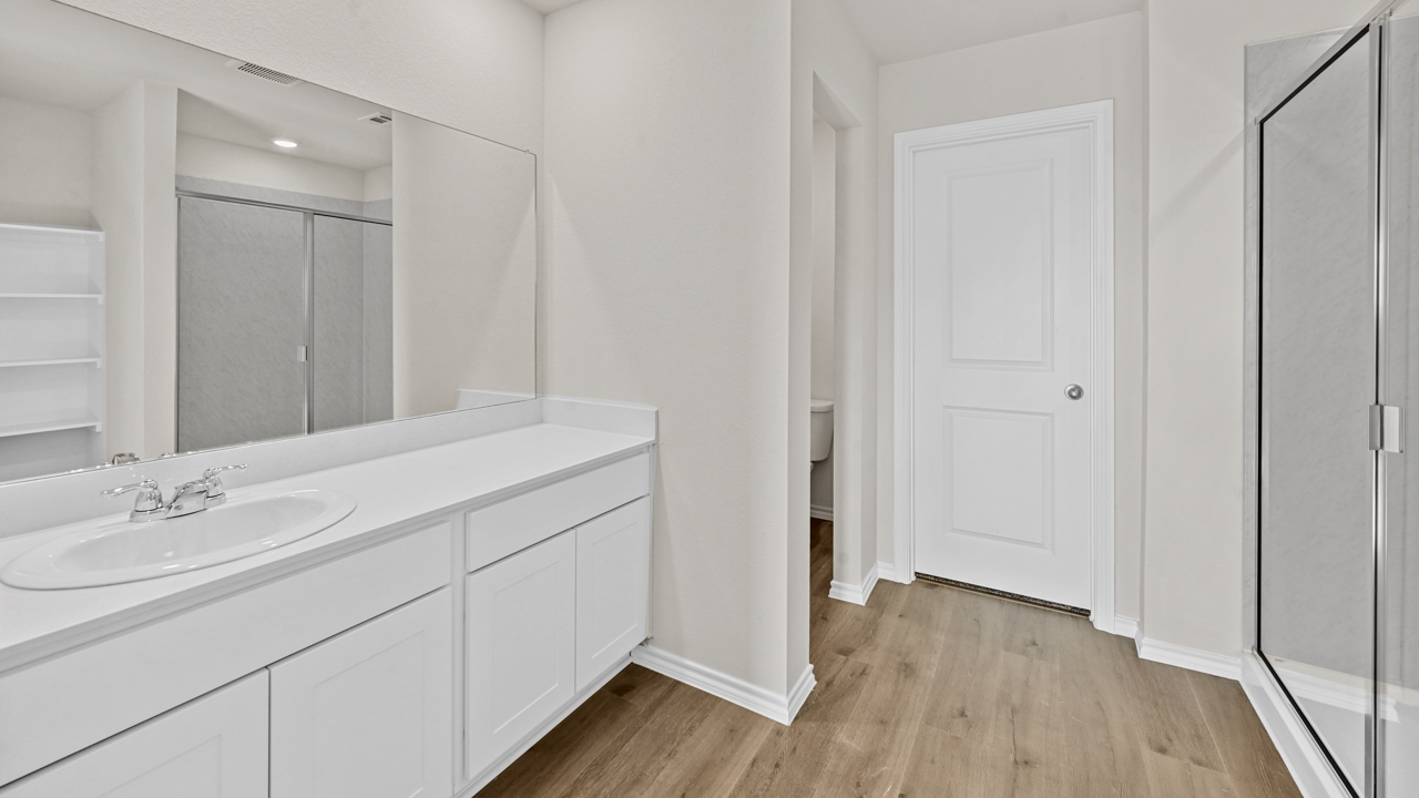 a bathroom with white cabinets and wood floors