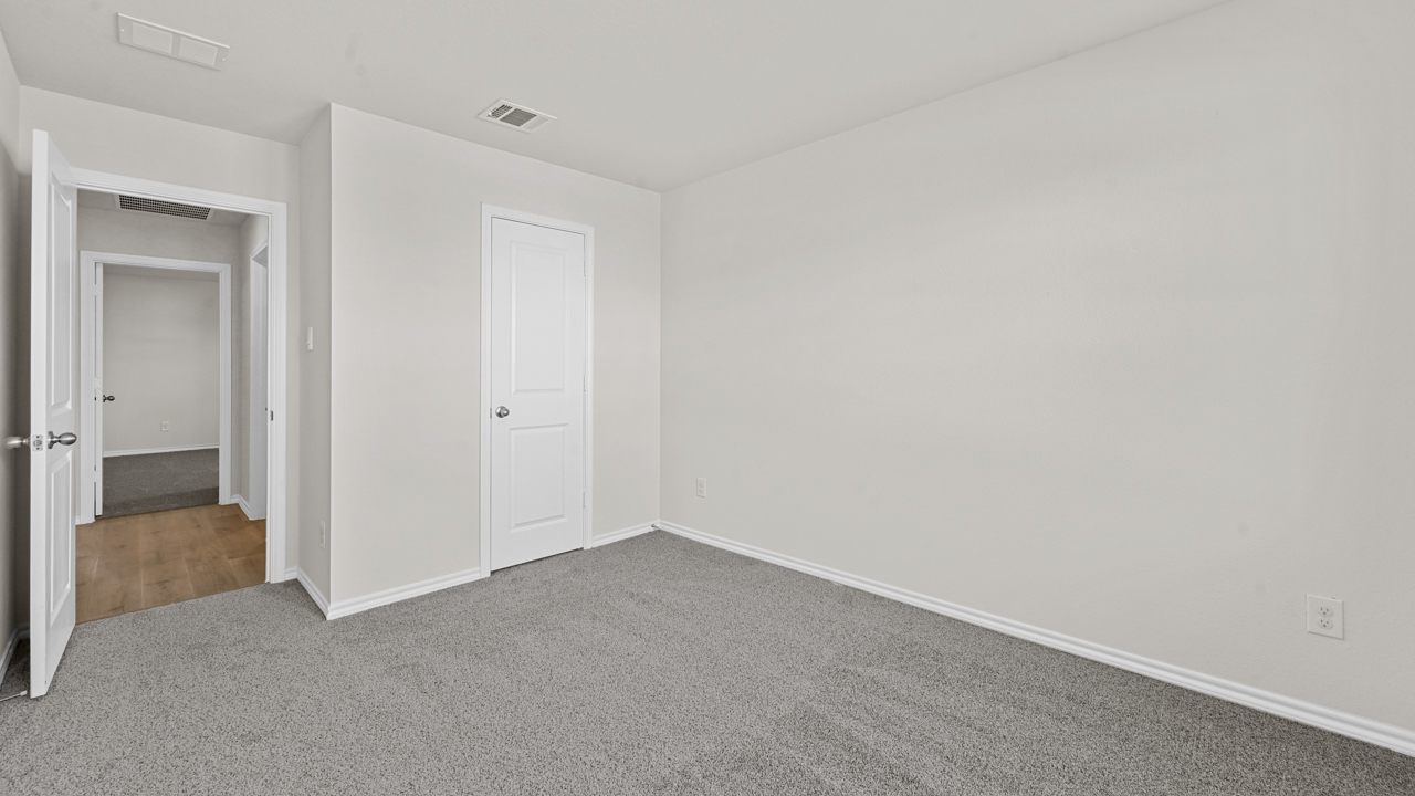 an empty bedroom with gray carpet and white walls