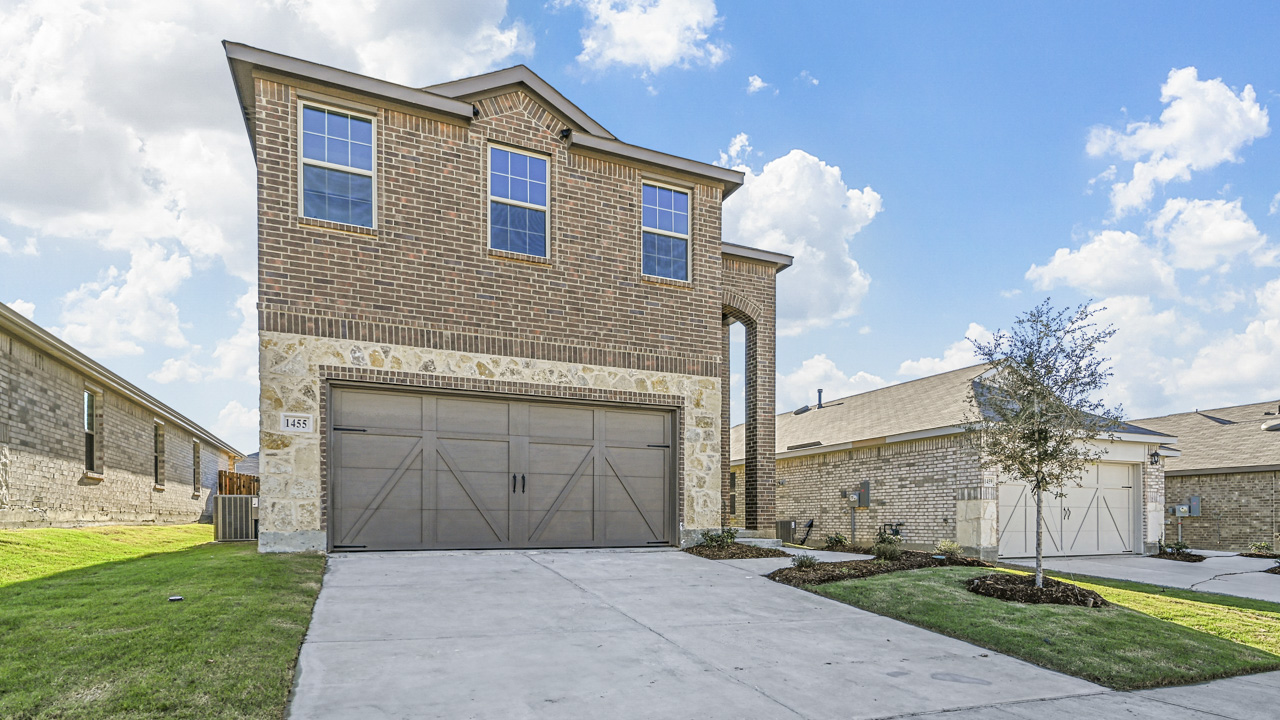 exterior of a brick two story home with a grass covered front yard and a concrete driveway in front