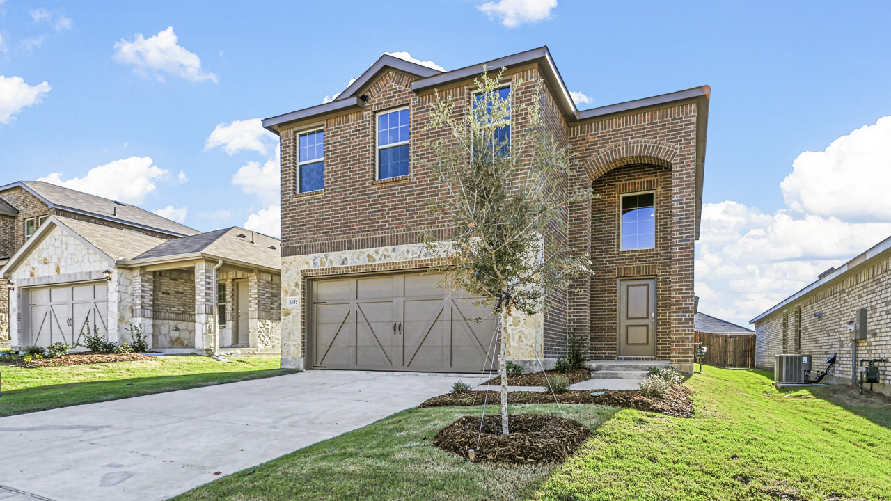 exterior of a brick two story home with a grass covered front yard and a concrete driveway in front