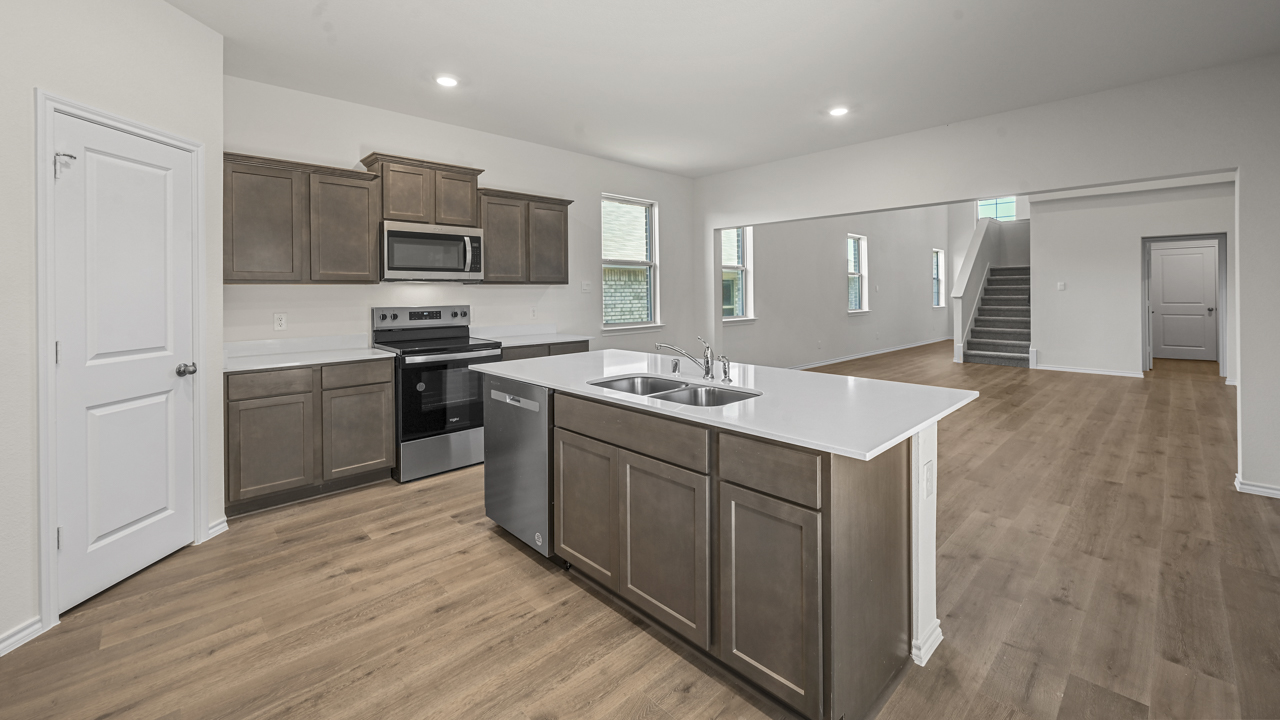 the open kitchen area with dark cabinets wood floors and an island in the middle