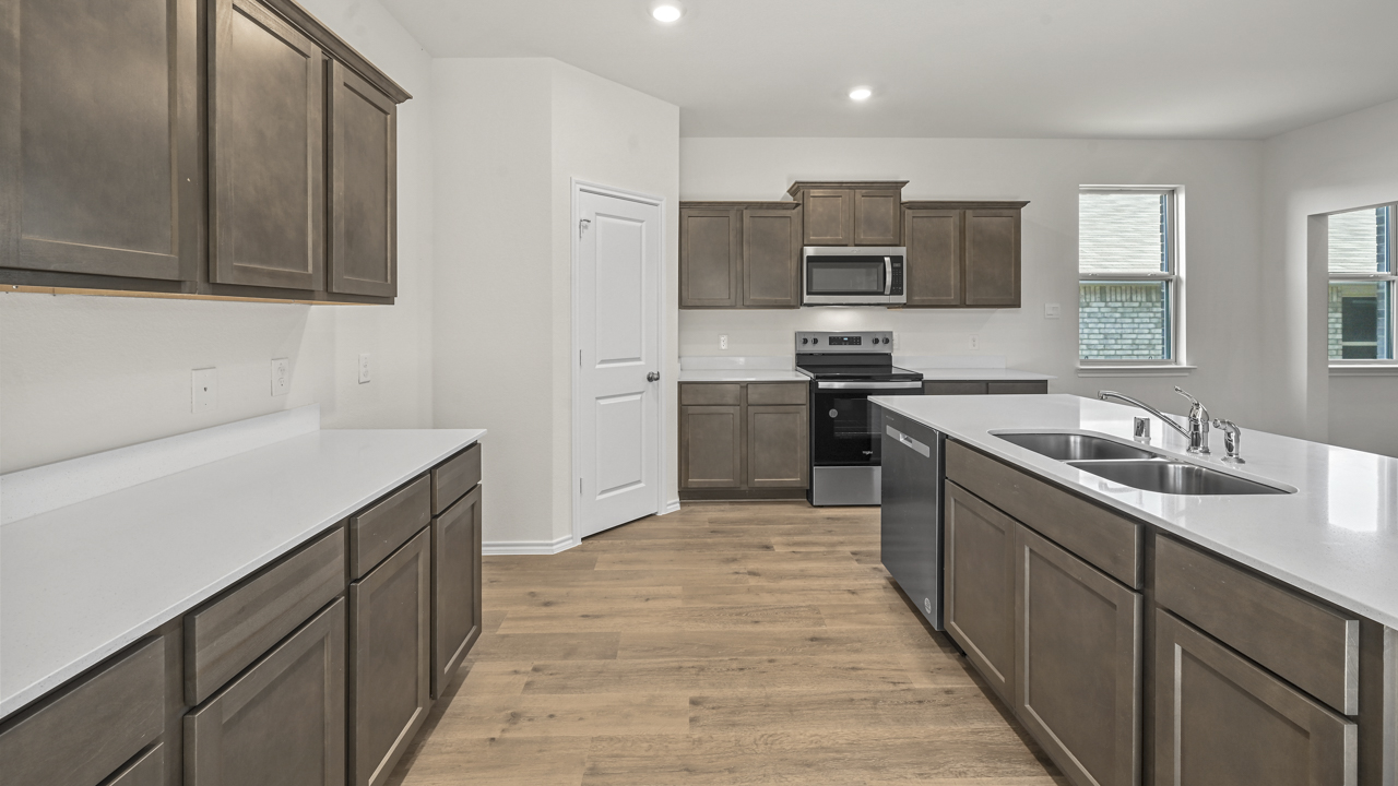 the open kitchen area with dark cabinets wood floors and an island in the middle