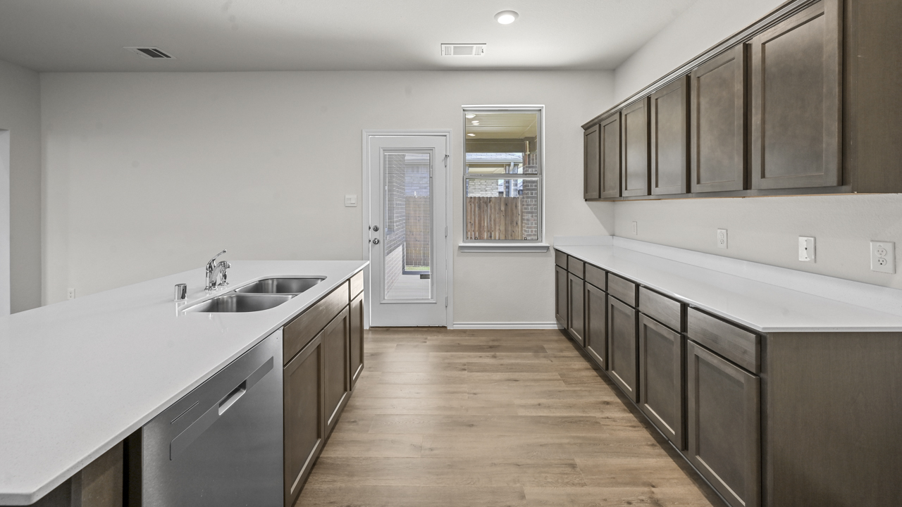 the open kitchen area with dark cabinets wood floors and an island in the middle