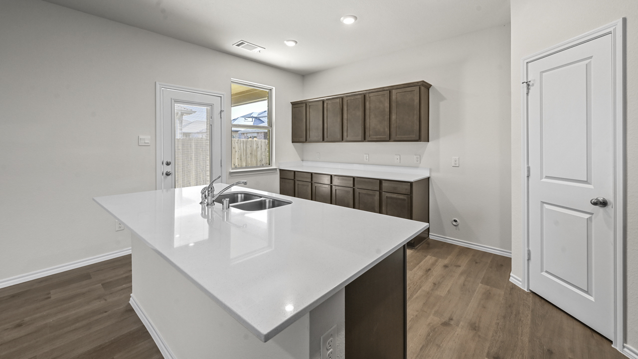 the open kitchen area with dark cabinets wood floors and an island in the middle
