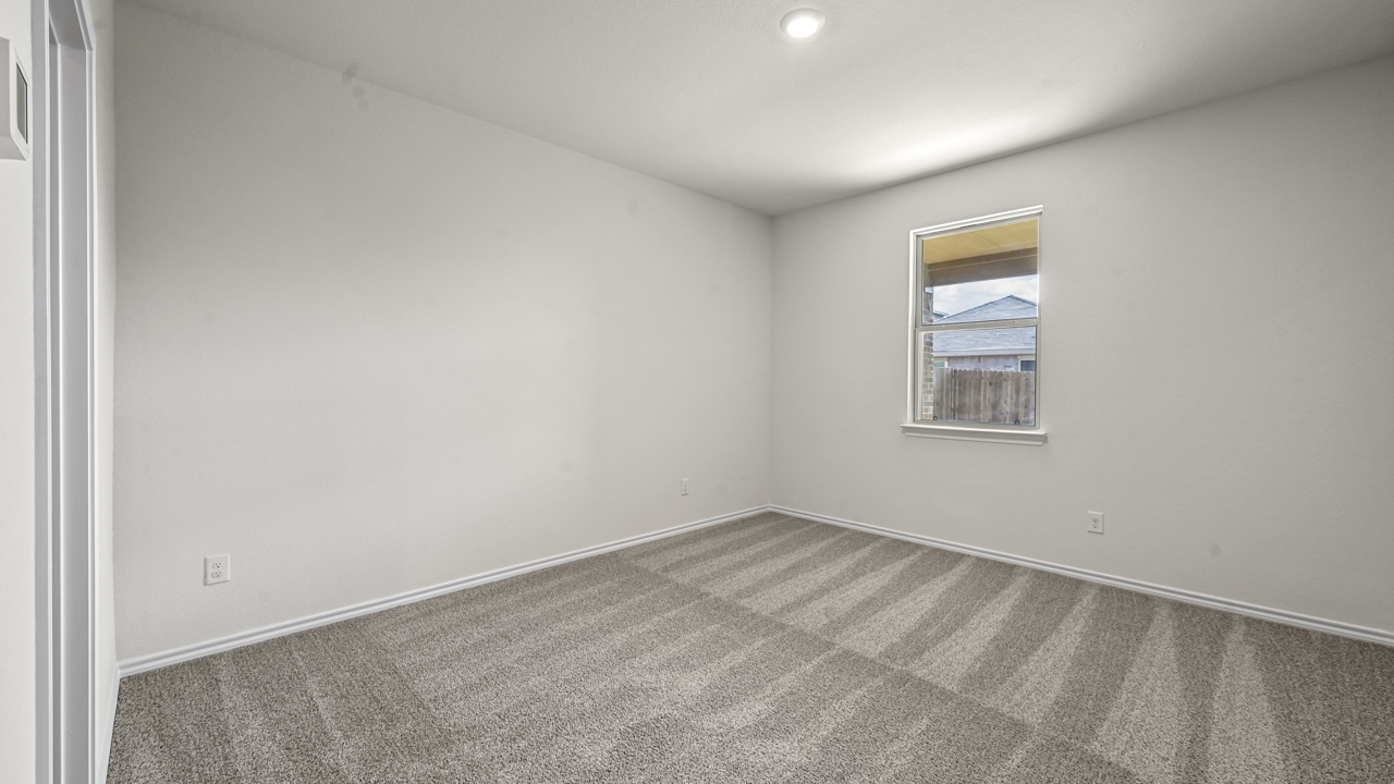 an empty bedroom with white walls and gray carpet