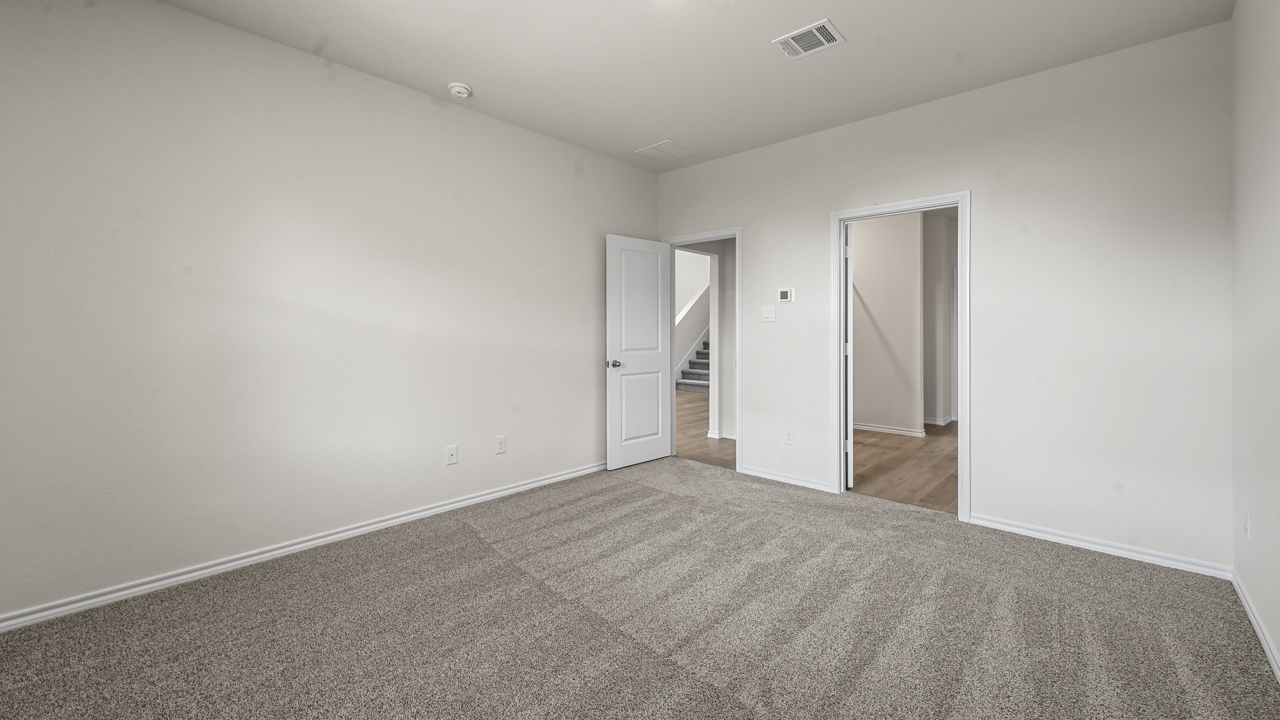 an empty bedroom with white walls and gray carpet