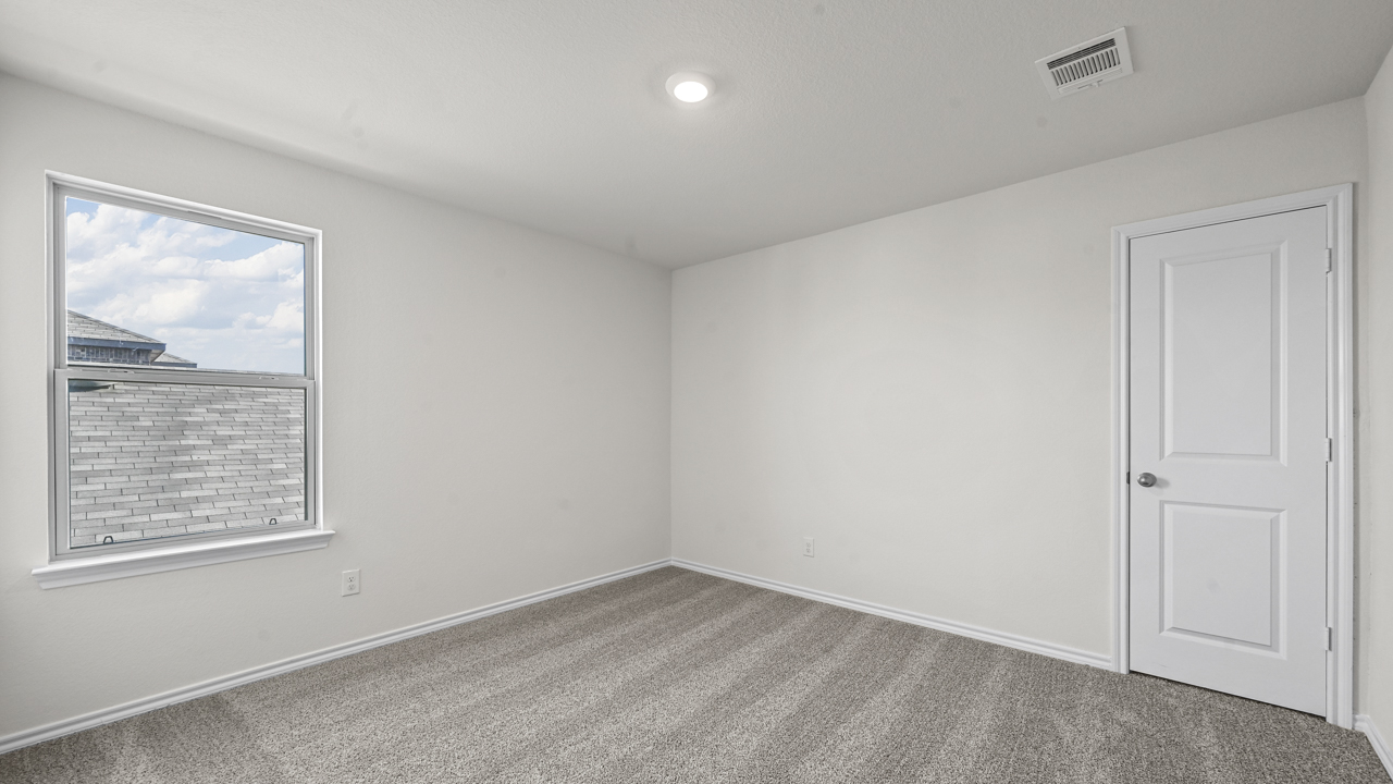 an empty bedroom with white walls and gray carpet