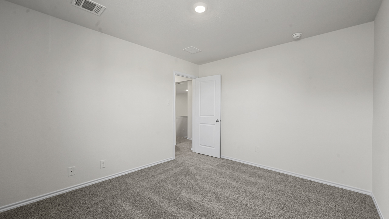 an empty bedroom with white walls and gray carpet