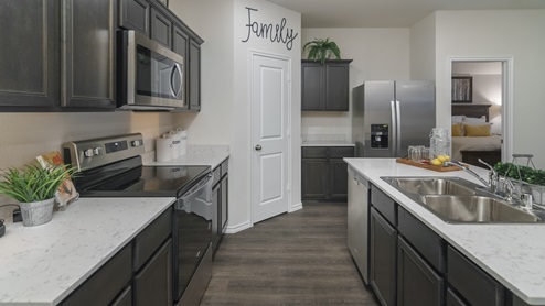 2914 Drury Lane at Stonewyck Farms in Ennis, TX kitchen area with hardwood floors dark cabinets and white counters
