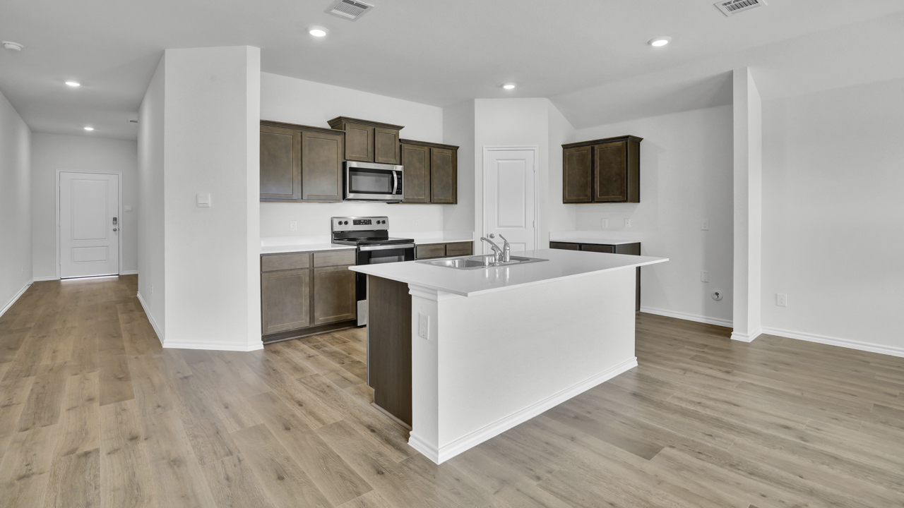 Kitchen area with light colored counters and dark cabinets with hardwood floors and kitchen island