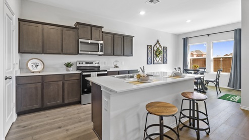 Kitchen island surrounded by brown cabinets and hard surface countertops