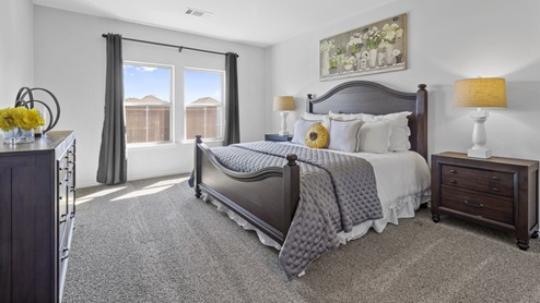 Large primary bedroom with large window and beautiful furnishings