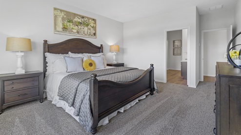 Large primary bedroom with large window and beautiful furnishings