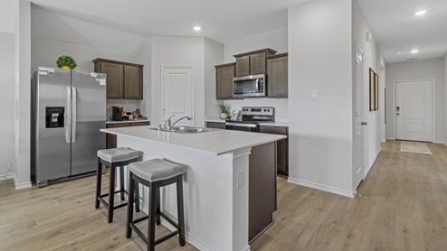 Kitchen island with hard surface countertops, brown cabinets and stainless steel appliances