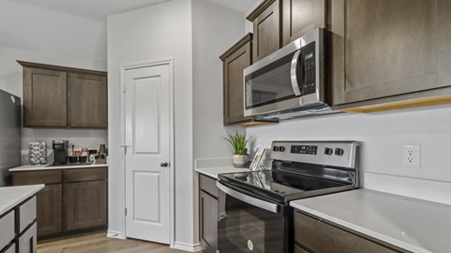 Kitchen with brown cabinets, stainless steel appliances and walk in pantry