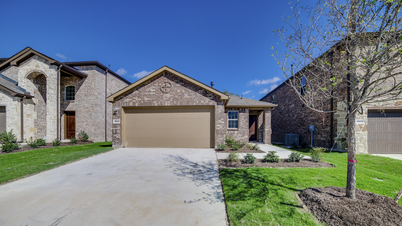 exterior of one story home with brick exterior left front entry to the home with two car garage and driveway