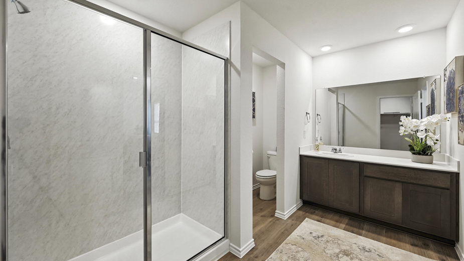bathroom with dual vanity sinks, toilet,  and a walk in shower
