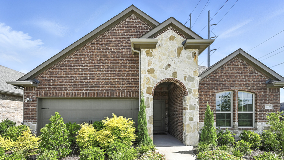 front exterior of a home with brick and stone exterior and a two car garage