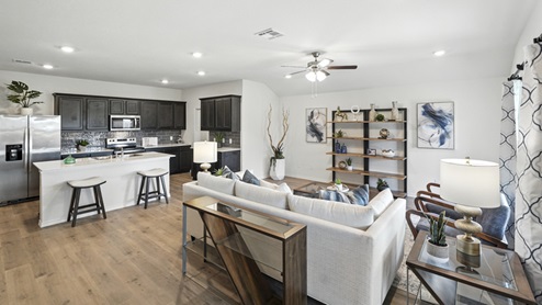 Main living area with clean flooring and natural light connecting to kitchen.