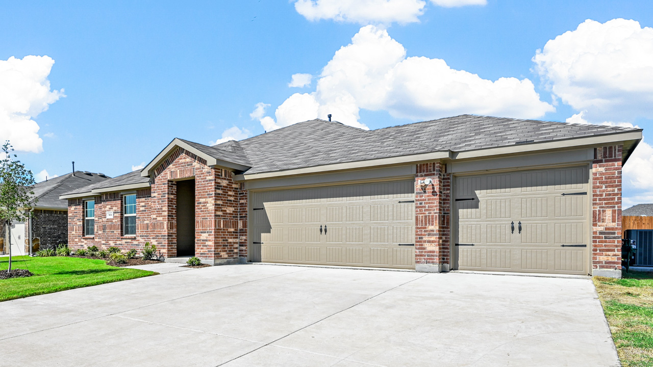 the exterior of a one story brick home with a three car garage
