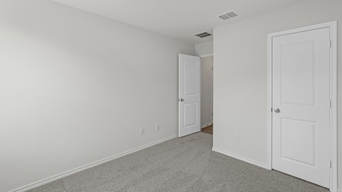 an empty bedroom with gray carpet and white walls