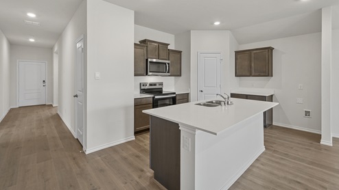 a kitchen with dark cabinets white walls and wood floors
