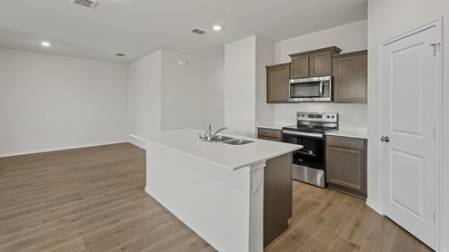 a kitchen with dark cabinets white walls and wood floors