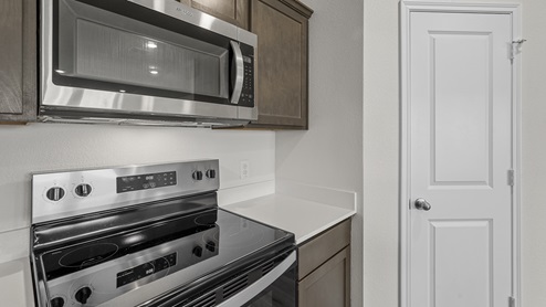 a kitchen with dark cabinets white walls and wood floors