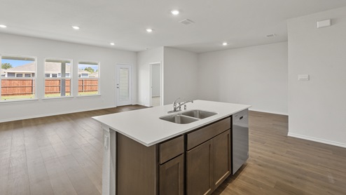 a kitchen with dark cabinets white walls and wood floors