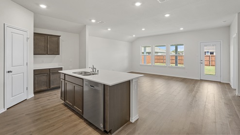 a kitchen with dark cabinets white walls and wood floors
