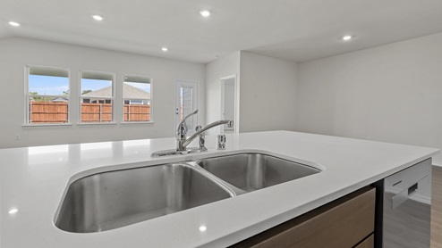 a kitchen with dark cabinets white walls and wood floors