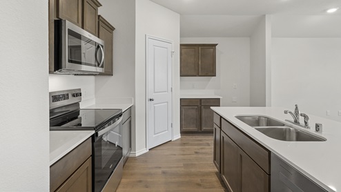 a kitchen with dark cabinets white walls and wood floors