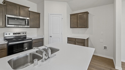 a kitchen with dark cabinets white walls and wood floors