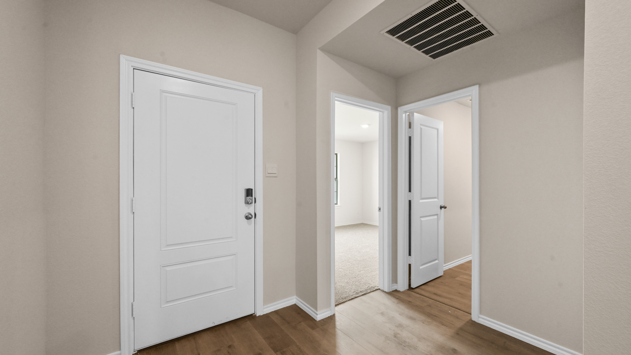 the interior entry of a home with white walls and wood floors