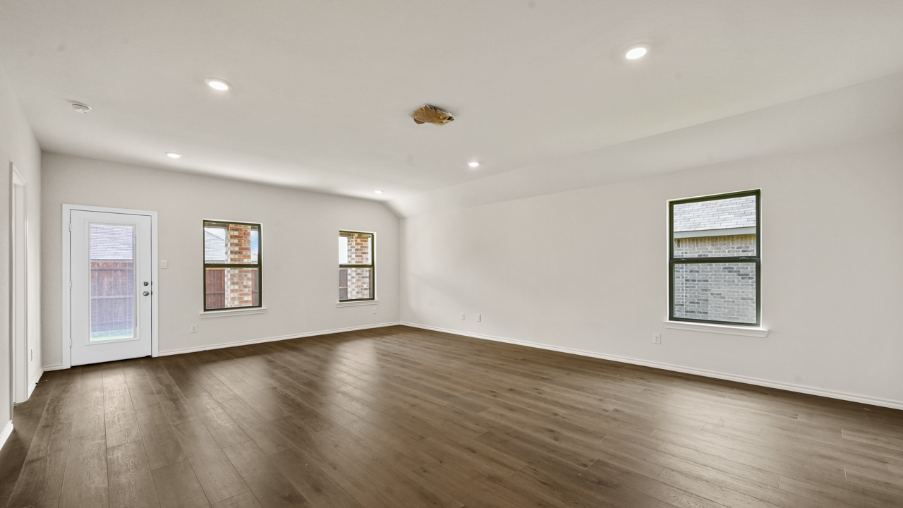 an empty living area with white walls and wood floors
