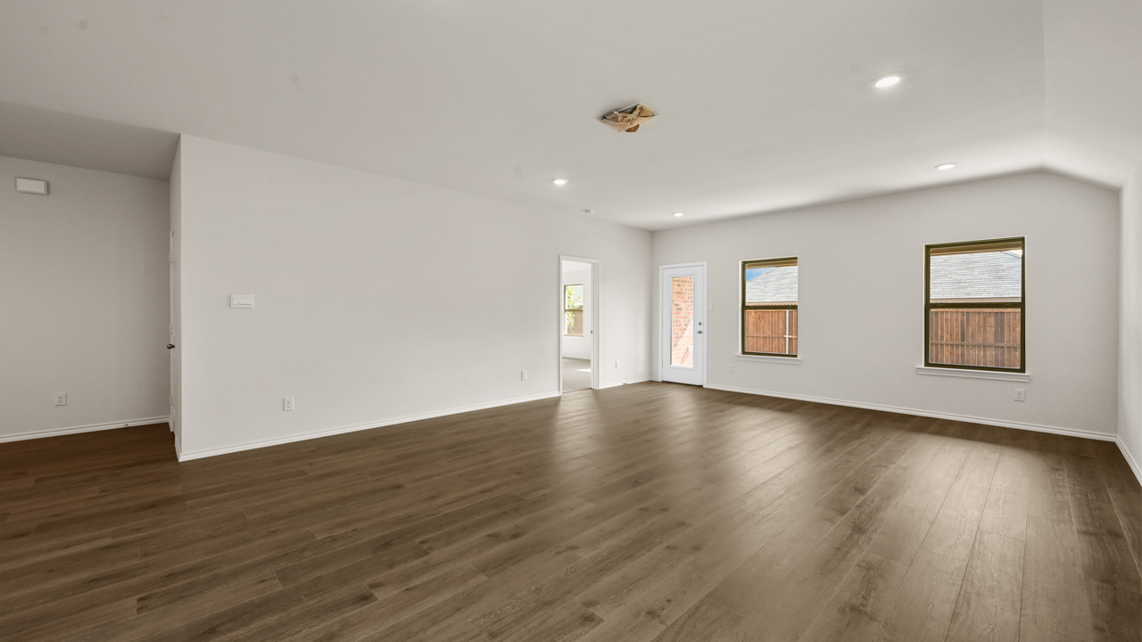 an empty living area with white walls and wood floors