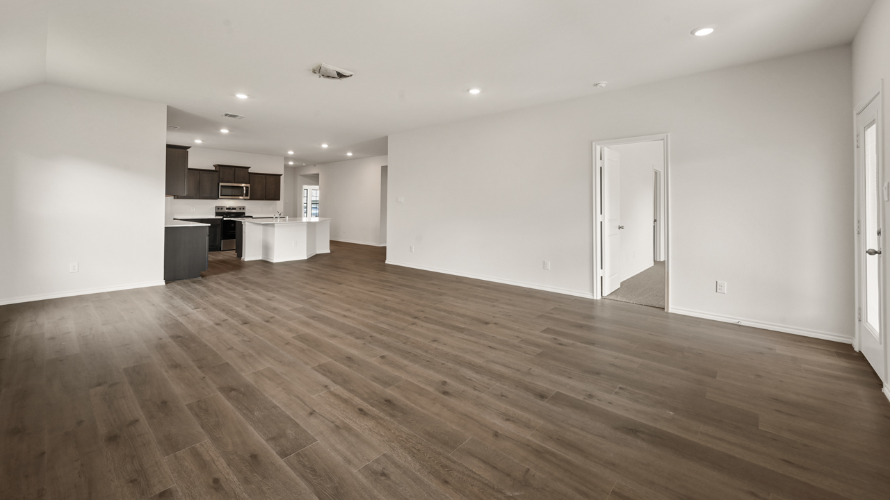 an empty living area with white walls and wood floors