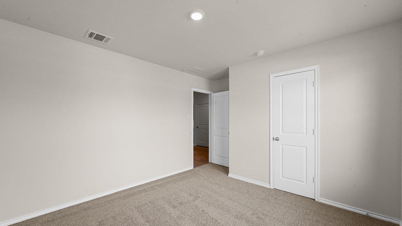an empty bedroom with gray carpet and white walls