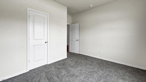 an empty bedroom with gray carpet and white walls