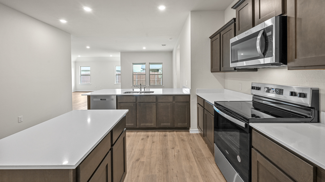 a kitchen with dark cabinets an island in the middle white walls and wood floors