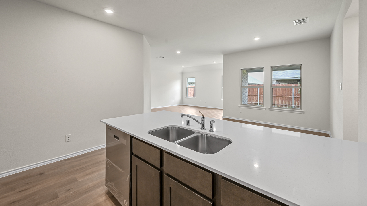 a kitchen with dark cabinets an island in the middle white walls and wood floors