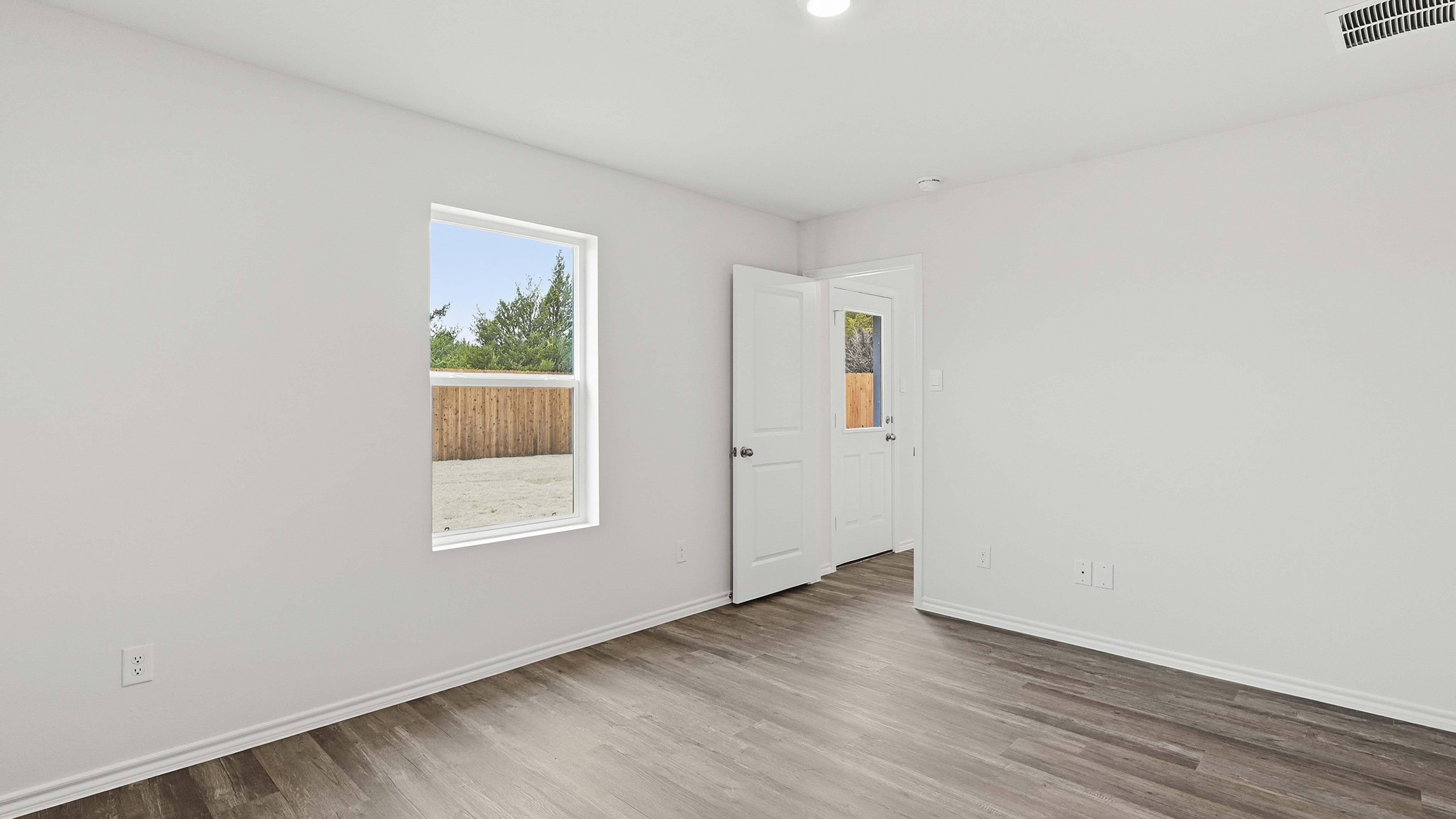 primary bedroom with hardwood floors and large windows facing the backyard