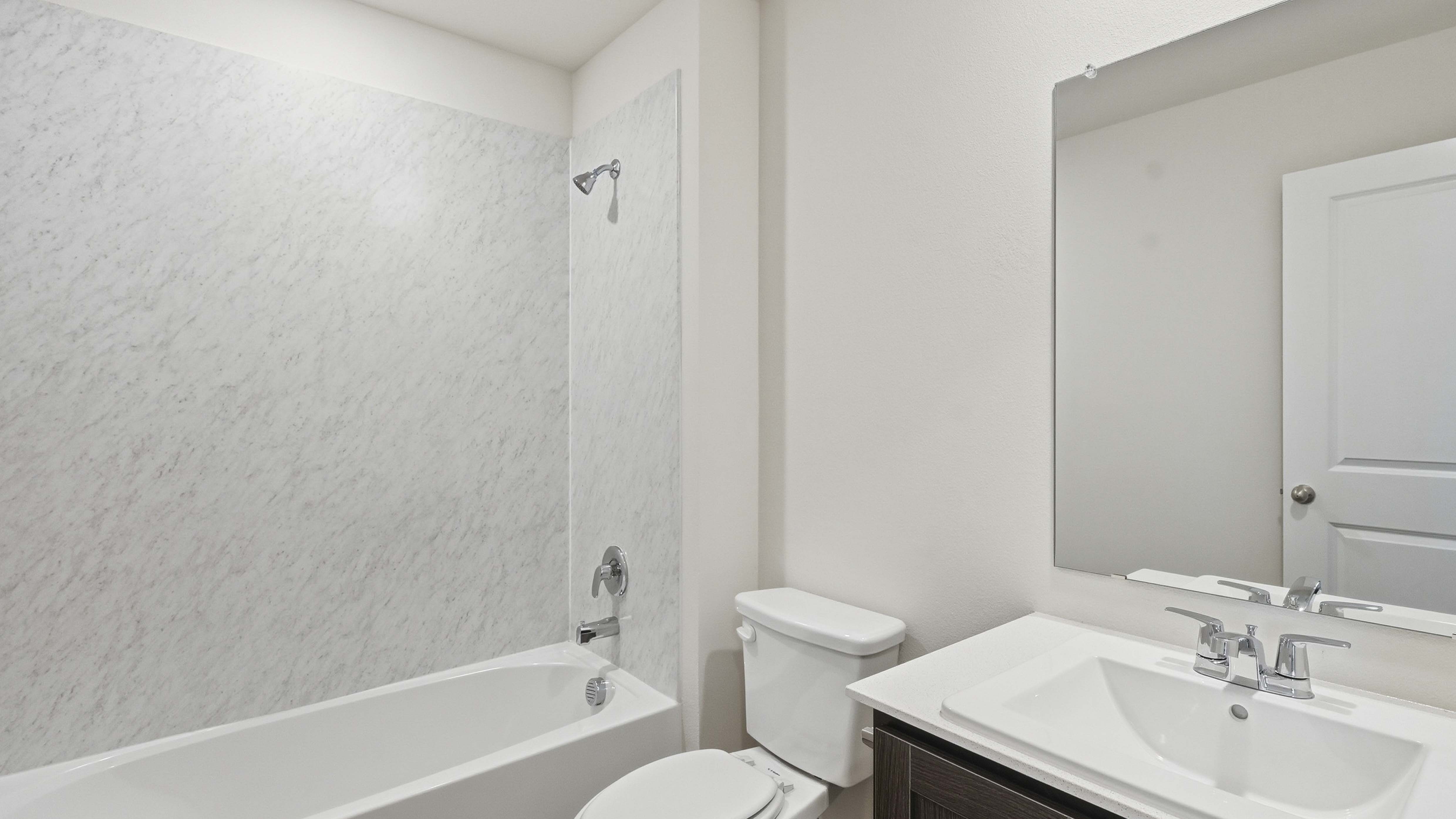 secondary bathroom with hardwood floors white counters and dark cabinets