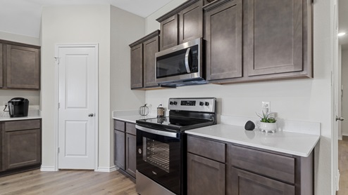 Kitchen Island surrounded by counters with hard surface countertops, brown cabinets and stainless steel appliances