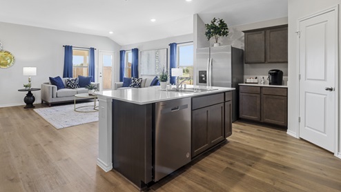 Kitchen Island with hard surface countertops, brown cabinets and views into the living room
