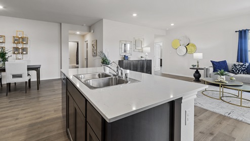 Kitchen Island with hard surface countertops, brown cabinets and views into the living room