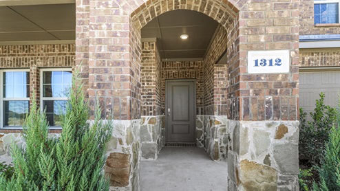 Close up of Two story model home with beautiful landscaping and covered patio