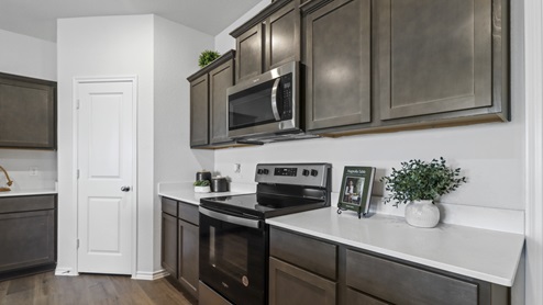 Kitchen island surrounded by white counters, brown cabinets and stainless steel appliances