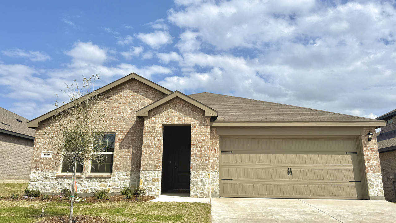 exterior of one story home with brick and stone and large windows facing the front yard